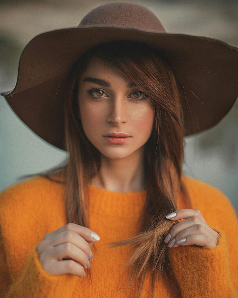 Elegant portrait of a woman in a hat and sweater outdoors in Paris.
